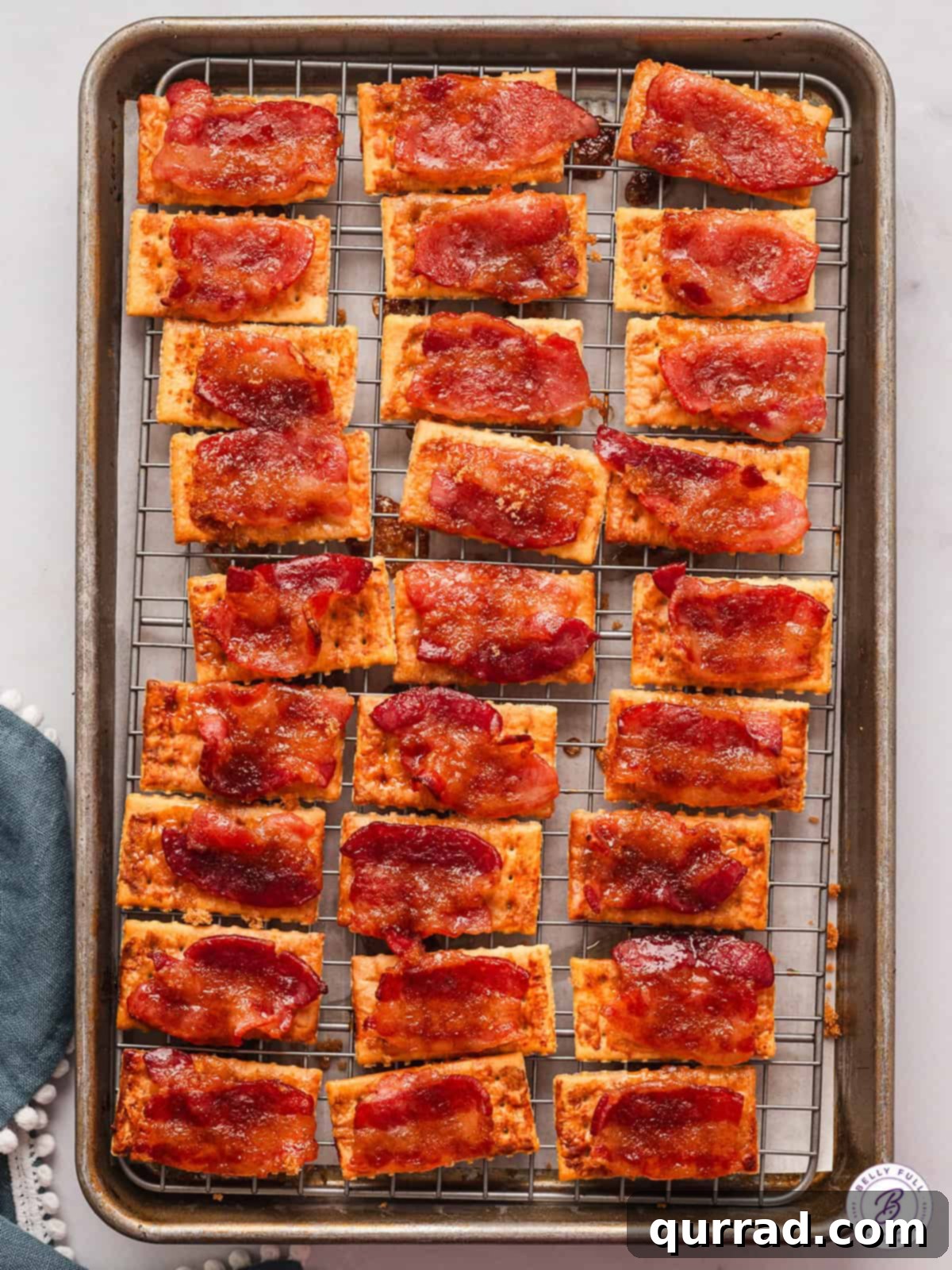 A baking sheet filled with perfectly golden, crispy candied bacon crackers, glistening with caramelized brown sugar.