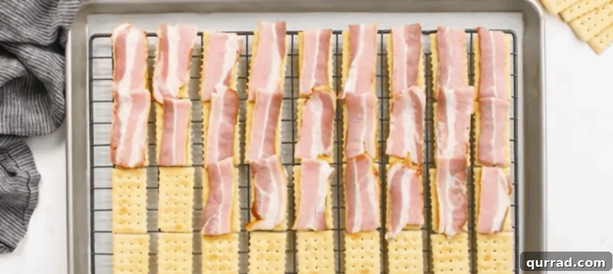 Pieces of raw bacon laid on top of each Club cracker, ready for seasoning.
