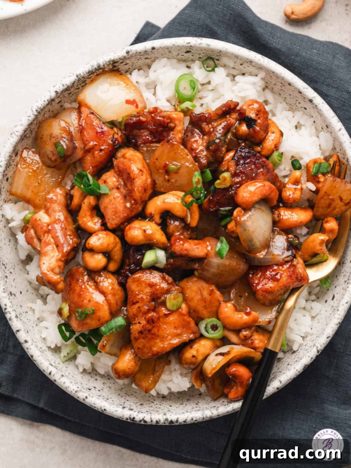 Grilled Peanut Chicken Skewers 5 Overhead view of a bowl of cashew chicken, rich with sauce, cashews, and vegetables, served alongside white rice.