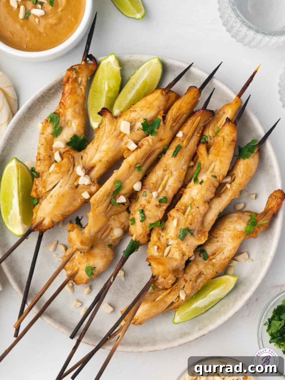 A mouthwatering spread of chicken satay and its signature peanut sauce, artfully presented with fresh lime. Overhead view of a beautifully arranged plate of chicken satay, accompanied by fresh lime wedges and a small bowl of creamy peanut sauce.