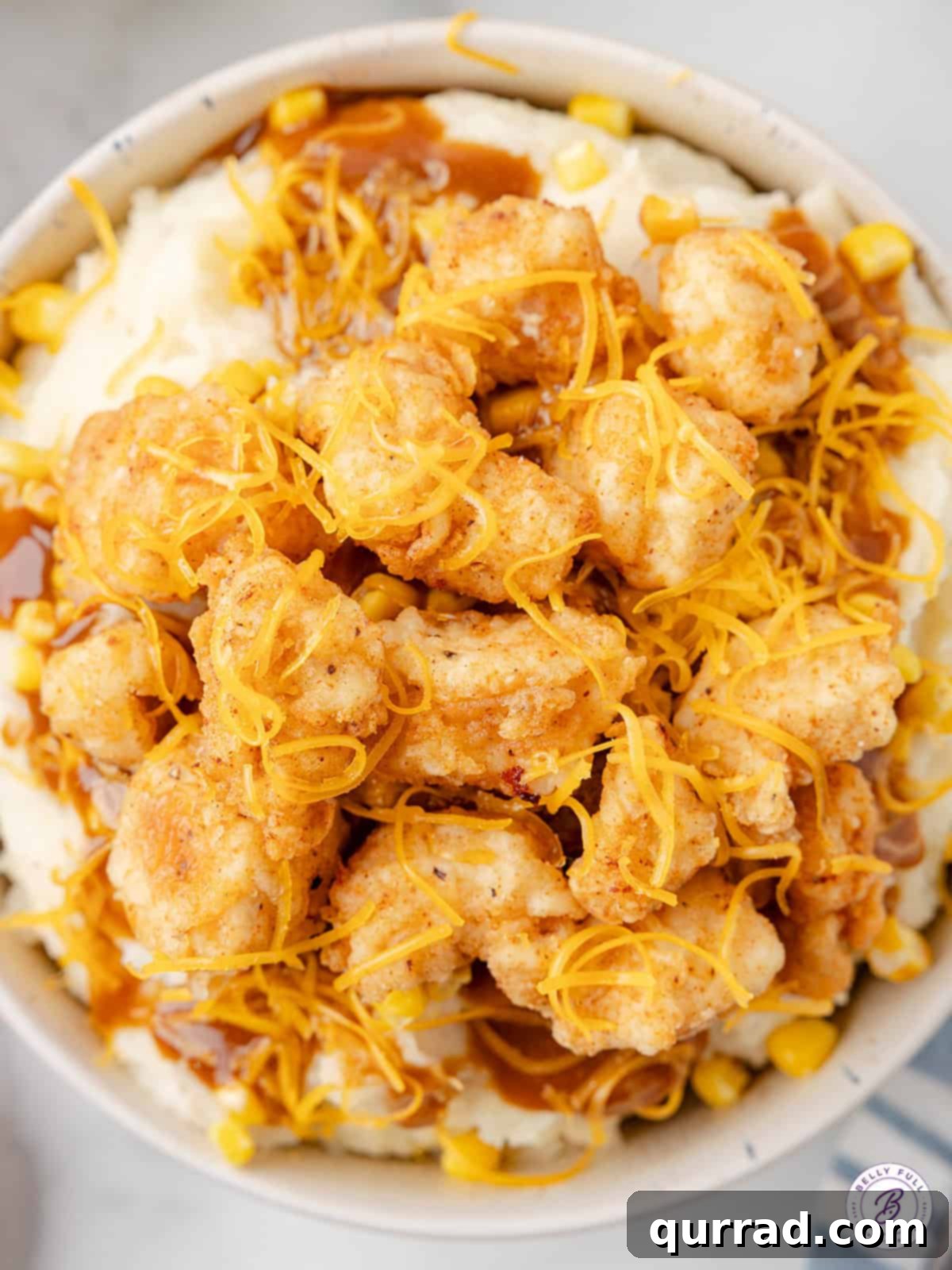 Overhead view of a copycat KFC bowl, showcasing crispy chicken, mashed potatoes, corn, gravy, and melted cheese