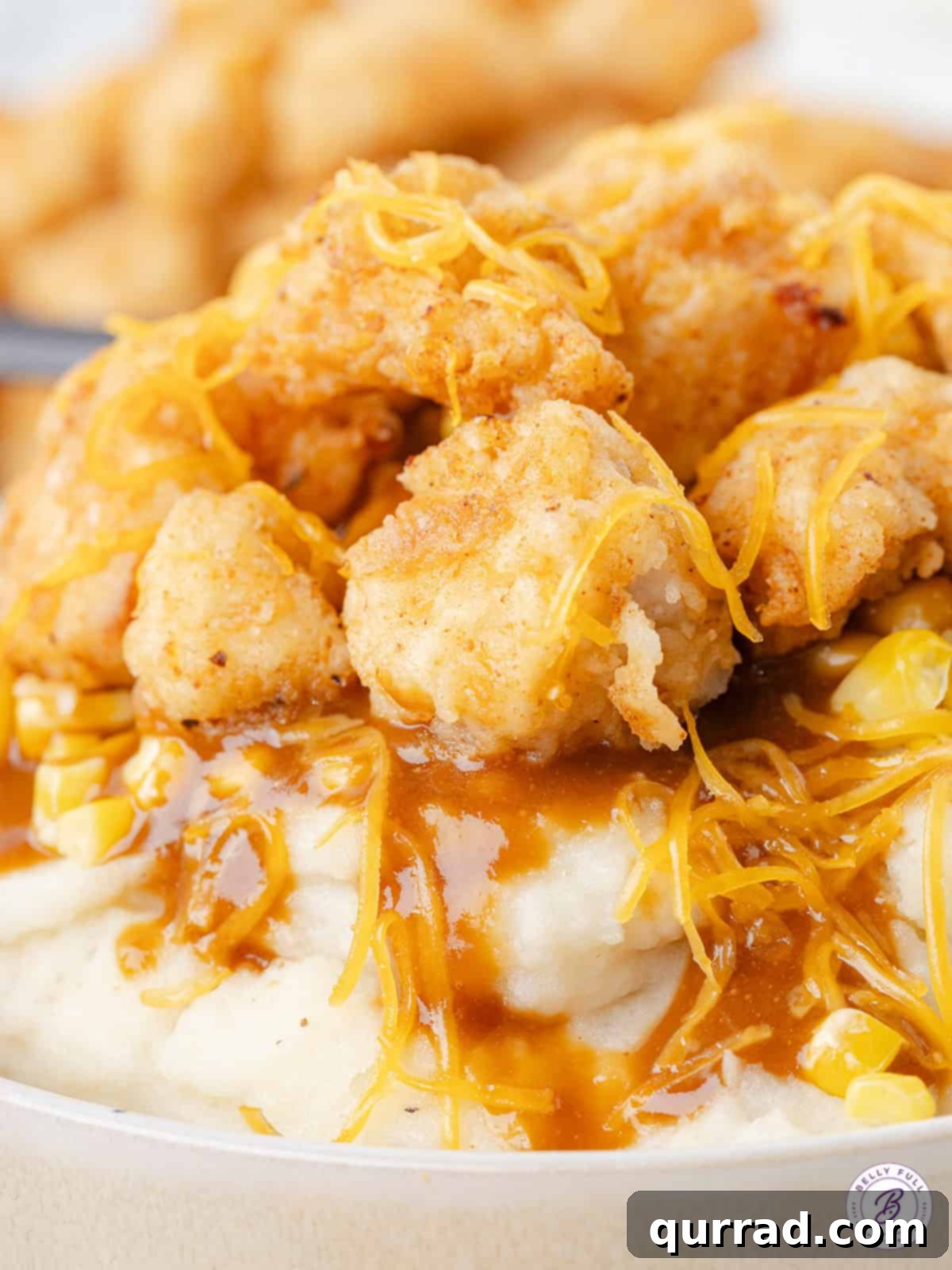 Close up of a copycat KFC Bowl, highlighting the texture of the chicken and the melted cheese
