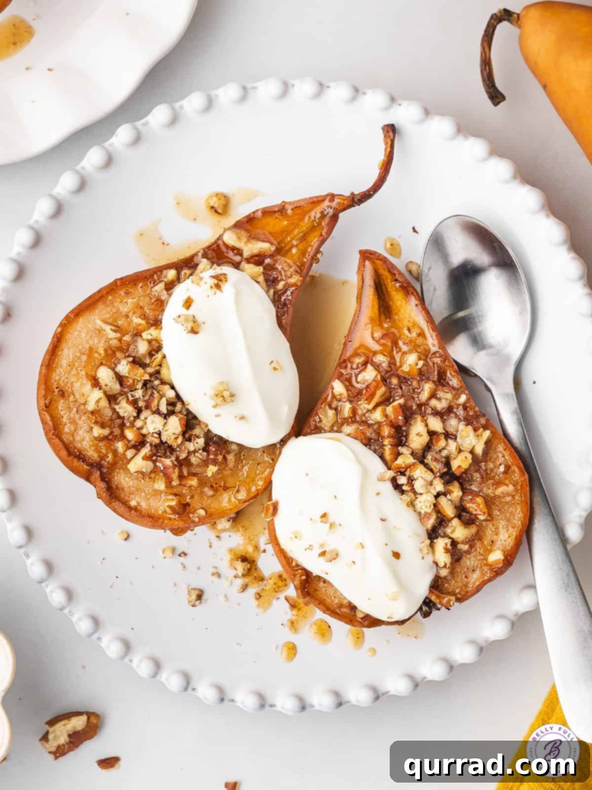 Perfectly spiced and sweetened with honey, this Baked Pears recipe requires just 5 ingredients. Serve with a scoop of vanilla ice cream. A close-up shot of a perfectly baked pear half, topped with a scoop of melting vanilla ice cream and a final drizzle of honey, on a white plate, emphasizing its enticing warmth and dessert appeal.
