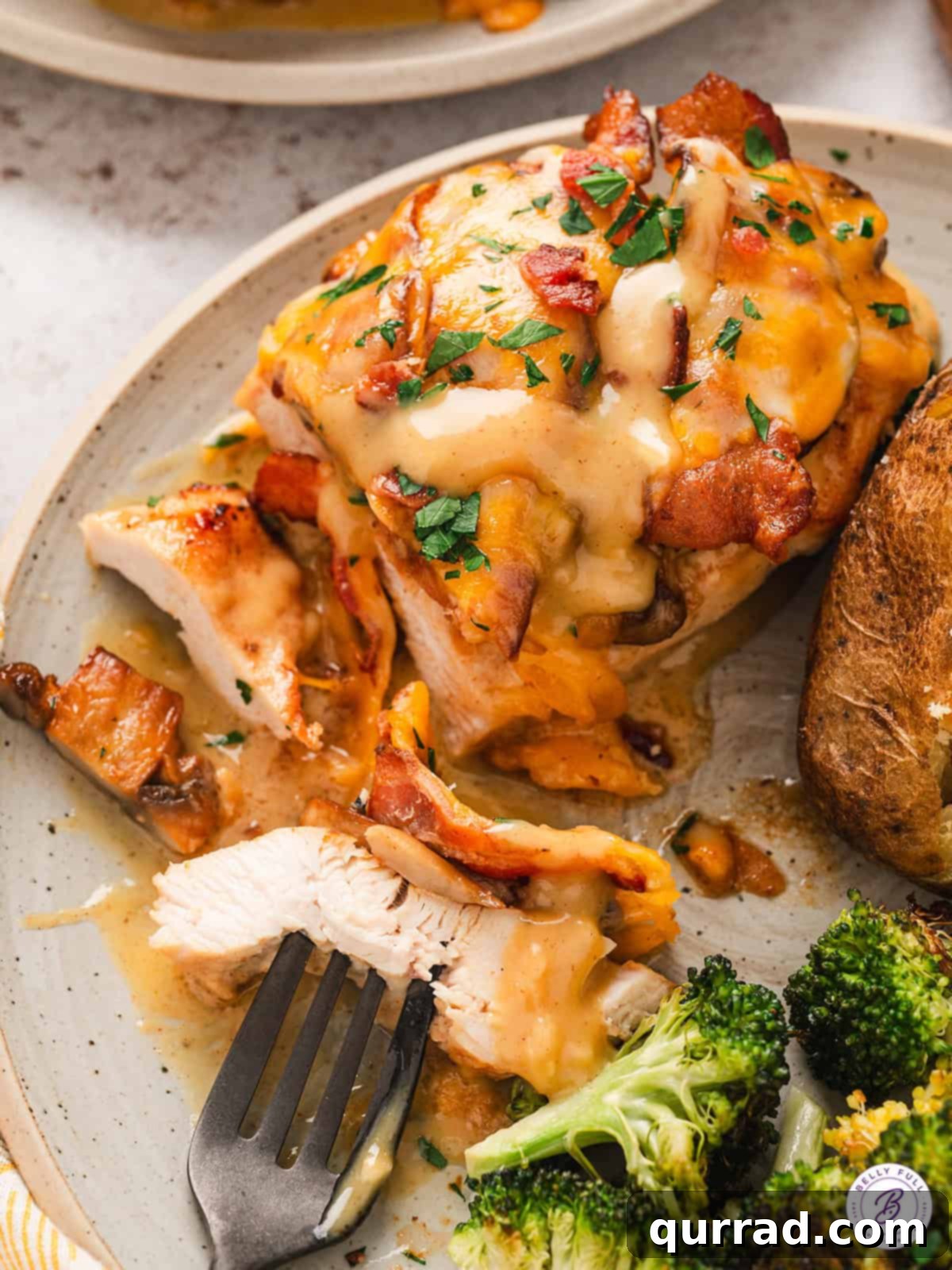 Alice Springs Chicken features juicy chicken breasts topped with a creamy honey mustard sauce, mushrooms, crispy bacon, and cheese. Alice Springs chicken on a plate with a few pieces sliced off and one piece on a fork.