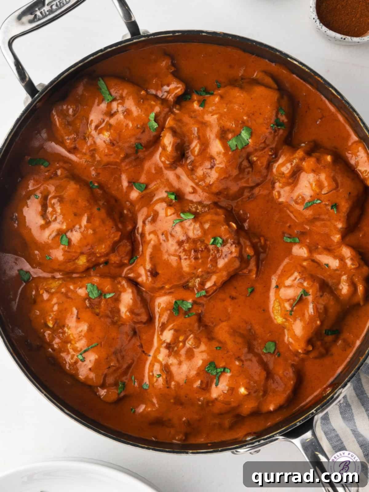 Chicken thighs simmered in a rich tomato-based sauce with Hungarian paprika, served over egg noodles. Overhead view of a skillet of chicken paprikash, ready to be served.
