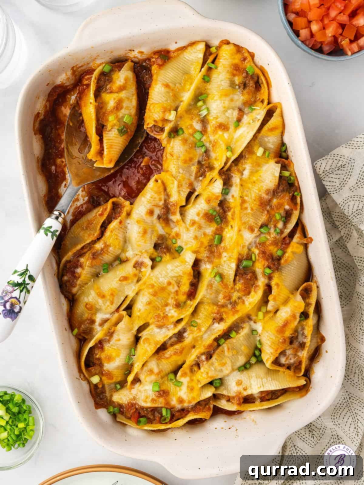 Jumbo pasta shells are stuffed with a mixture of taco meat, diced tomatoes, and cheese in this easy Taco Stuffed Shells recipe. Overhead view of a pan of golden-brown taco stuffed shells, ready to serve.