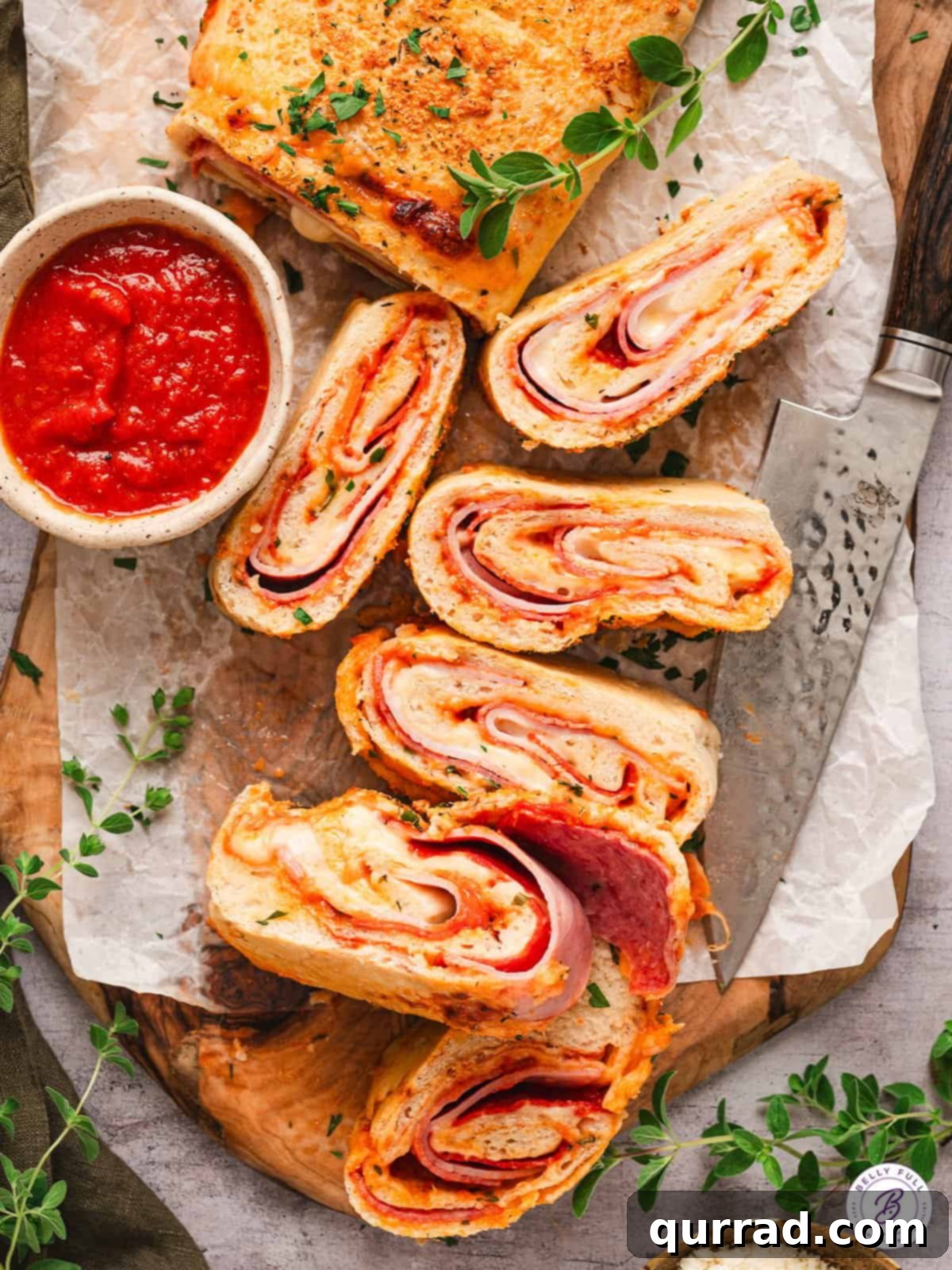 Overhead view of several slices of stromboli neatly arranged on a platter, accompanied by a small bowl of pizza sauce for dipping.