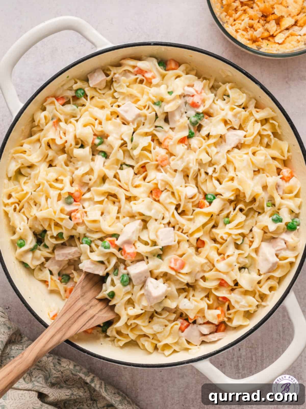 Homemade Chicken Noodle Casserole: Easy & Delicious Overhead view of chicken and noodle casserole with a wooden spoon, ready to be served