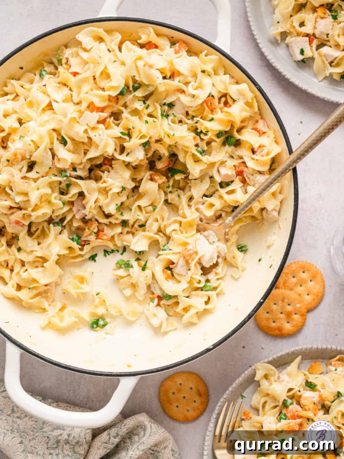 Preparing Homemade Chicken Noodle Casserole A wooden spoon stirring creamy chicken noodle casserole in a skillet