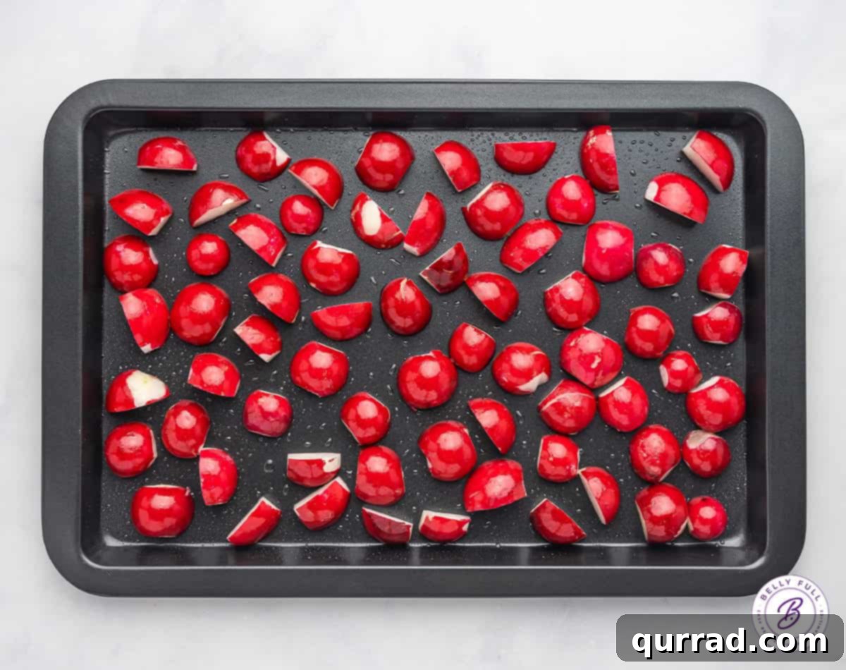 Radish halves neatly arranged on a baking sheet before roasting.