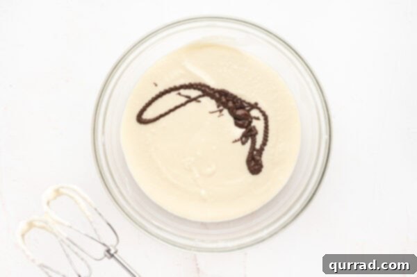 French silk pie filling being prepared, with melted chocolate slowly drizzled into the creamy base.