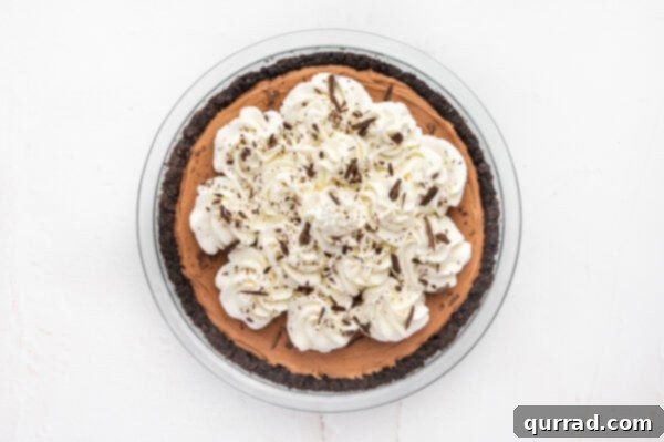 A beautifully finished French silk pie, adorned with swirls of whipped cream and delicate shavings of chocolate.