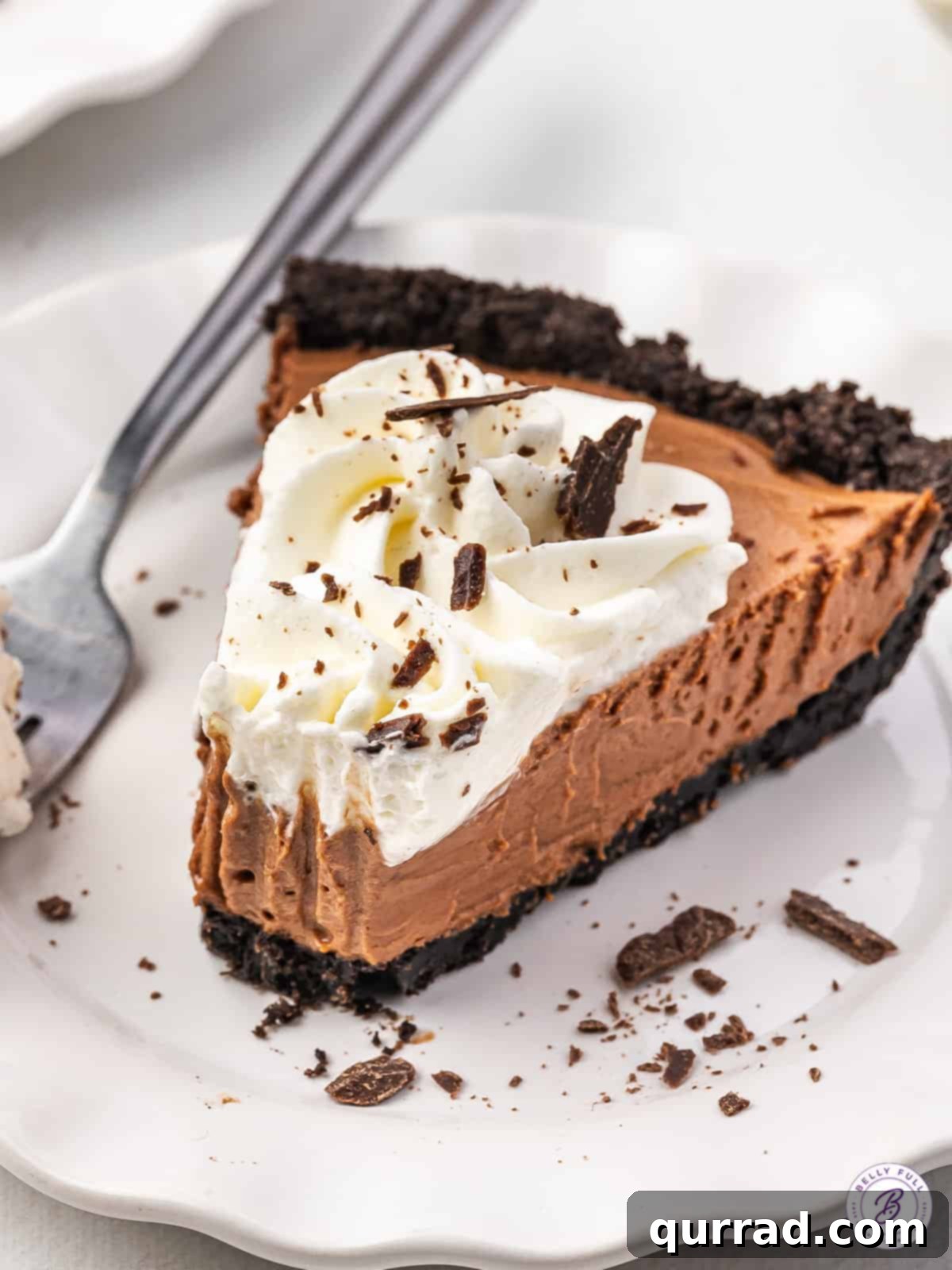 Decadent Chocolate Silk Pie 5 A mouth-watering side view of a slice of French Silk Pie on a white plate, with a forkful already taken, highlighting its creamy texture.