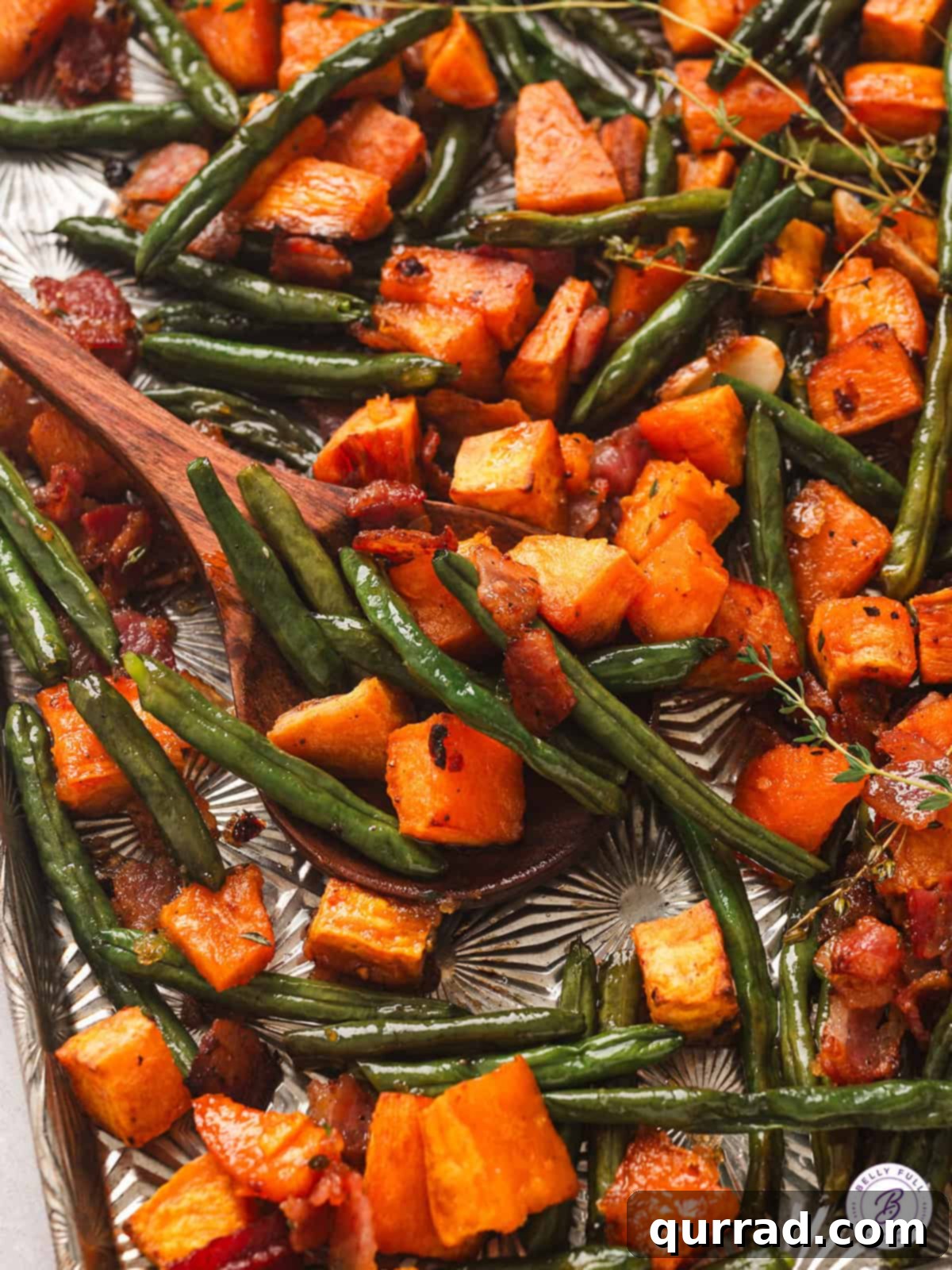 A delicious Sheet Pan Sweet Potato Supper featuring roasted sweet potatoes, green beans, and bacon – an easy and flavorful side dish or light dinner. Close up of roasted sweet potato supper, showing caramelized sweet potatoes, vibrant green beans, and crispy bacon pieces. The dish is perfectly browned and glistening, ready to be served.