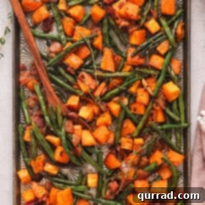 Overhead view of roasted sweet potatoes and green beans on a baking sheet