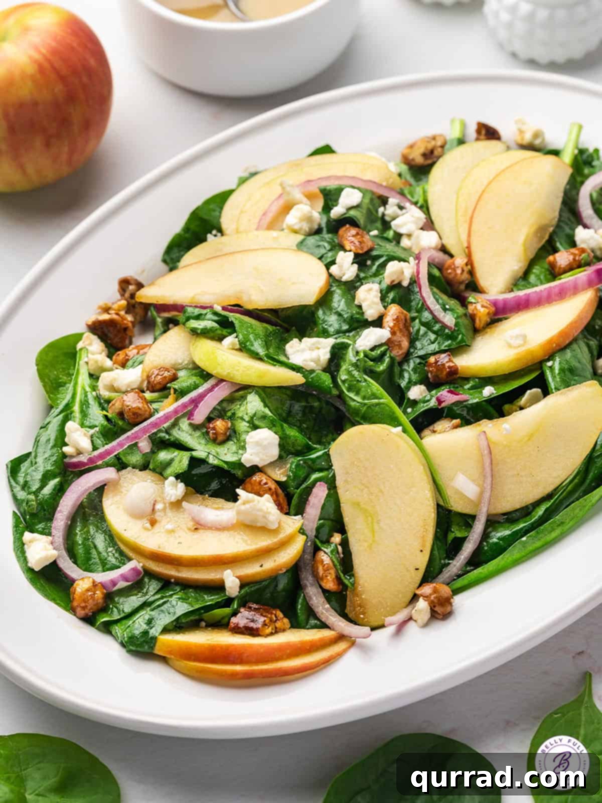A beautifully presented spinach apple salad on a pristine white platter, ready to be served.