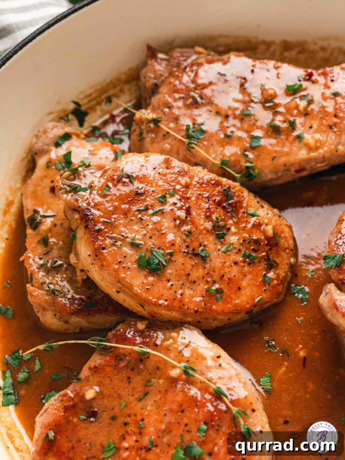 Pork chops with apple cider glaze in a skillet, glistening and ready to serve