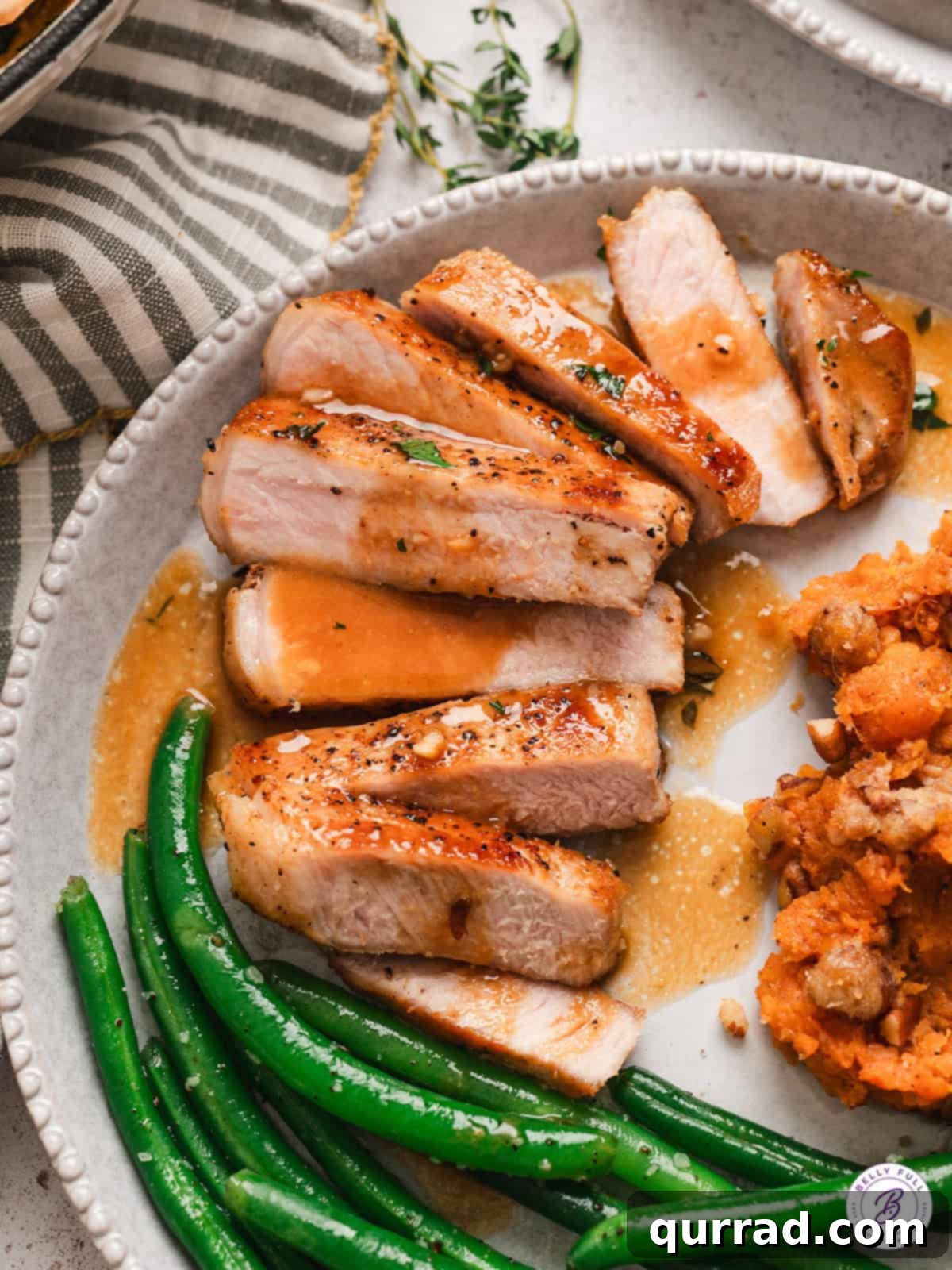 Pork chops with apple cider glaze on a plate accompanied by vibrant green beans