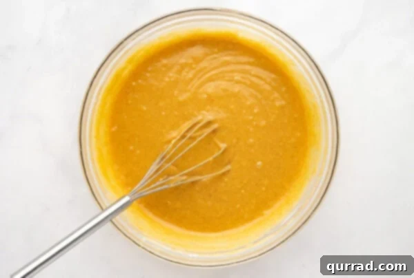Whisking pumpkin cake batter ingredients in a bowl