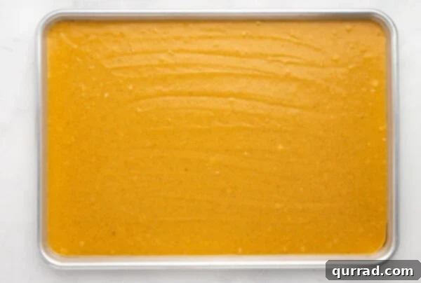 Pumpkin cake batter spread evenly in a sheet pan