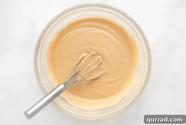 Whisking together ingredients for cinnamon frosting in a bowl