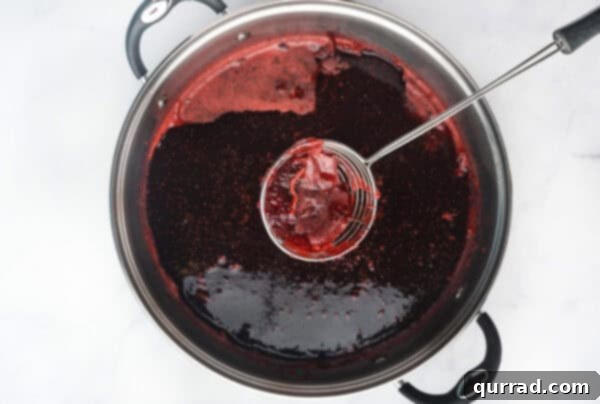 Yuletide Grooves 7 Skimming foam from the top of the freshly cooked jam in a pot.