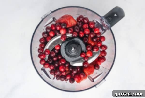 Yuletide Grooves 4 Cranberries and strawberries in the bowl of a food processor, ready to be pulsed.