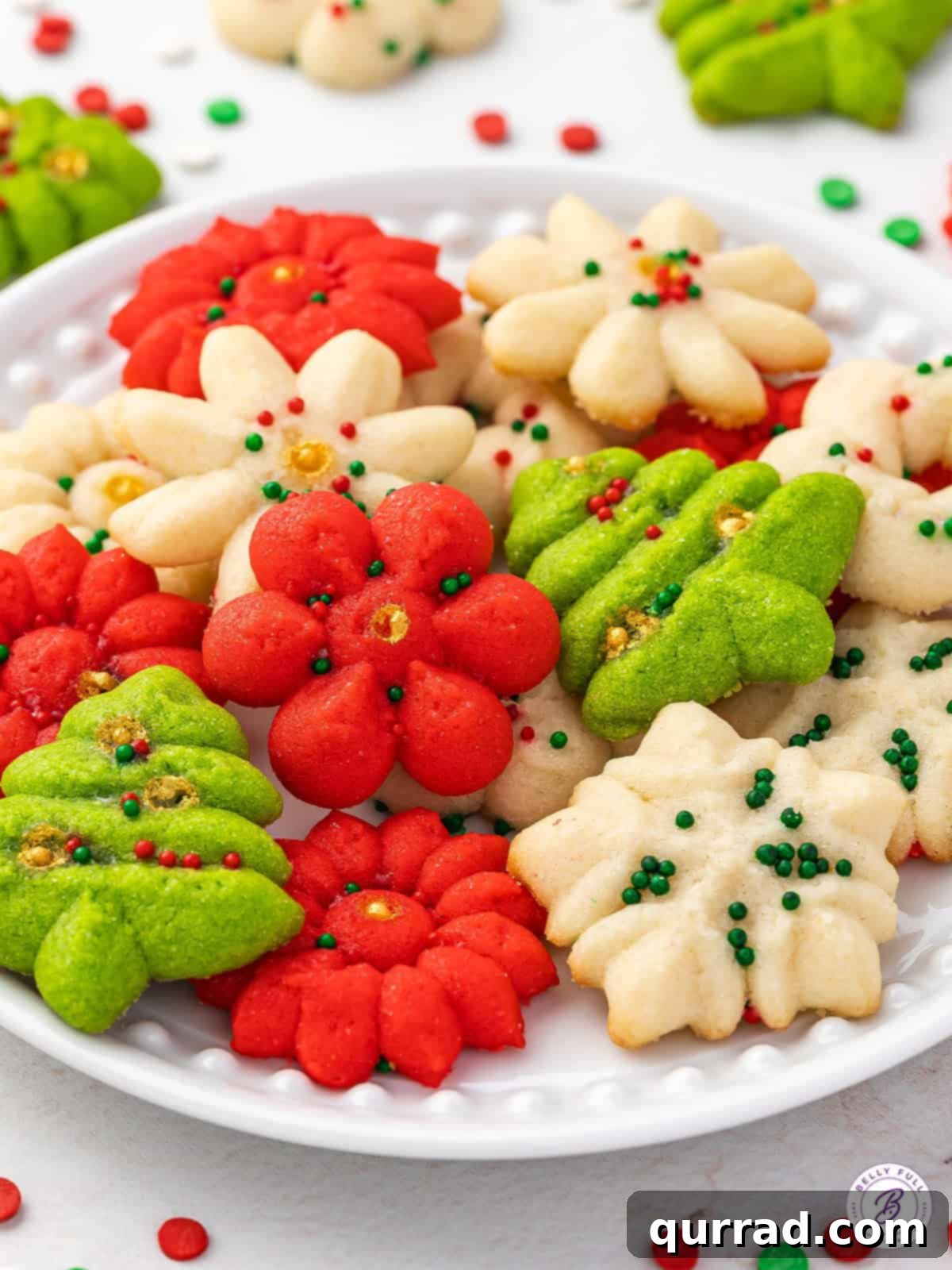 Pressed Butter Cookies 4 Side view of elegantly arranged Christmas spritz cookies on a white plate, showcasing their varied shapes and festive sprinkles.