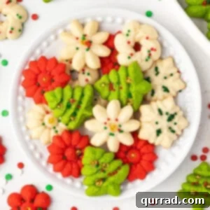 Overhead view of festive Christmas spritz cookies on a white plate, highlighting their various shapes and vibrant decorations.