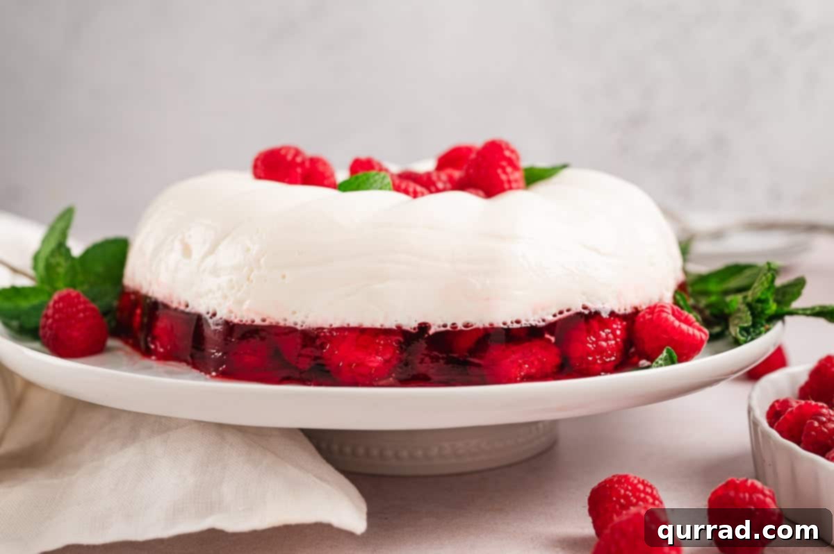 Crimson Snowcap Gelatin 2 Snowy raspberry jello mold on a festive serving platter, highlighting its dual-layer design.