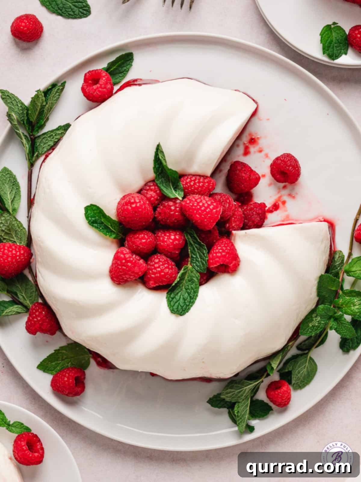 Raspberry jello is topped with a creamy white jello mixture in this Snowy Raspberry Jello recipe. Festive and perfect for the holidays! Overhead view of snowy raspberry jello mold with a slice removed, showing the distinct two layers.
