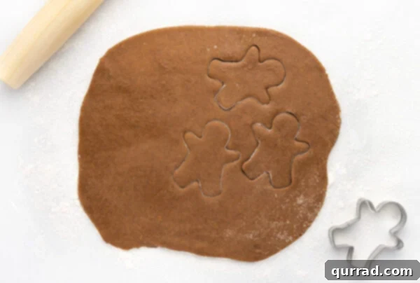 Gingerbread cookie dough rolled out into an even rectangle on a floured surface, ready for cutting.