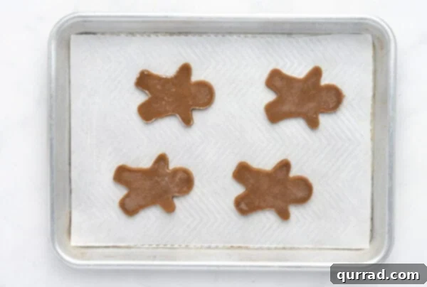 Unbaked gingerbread man cookies neatly arranged on a parchment-lined baking sheet, ready for the oven.