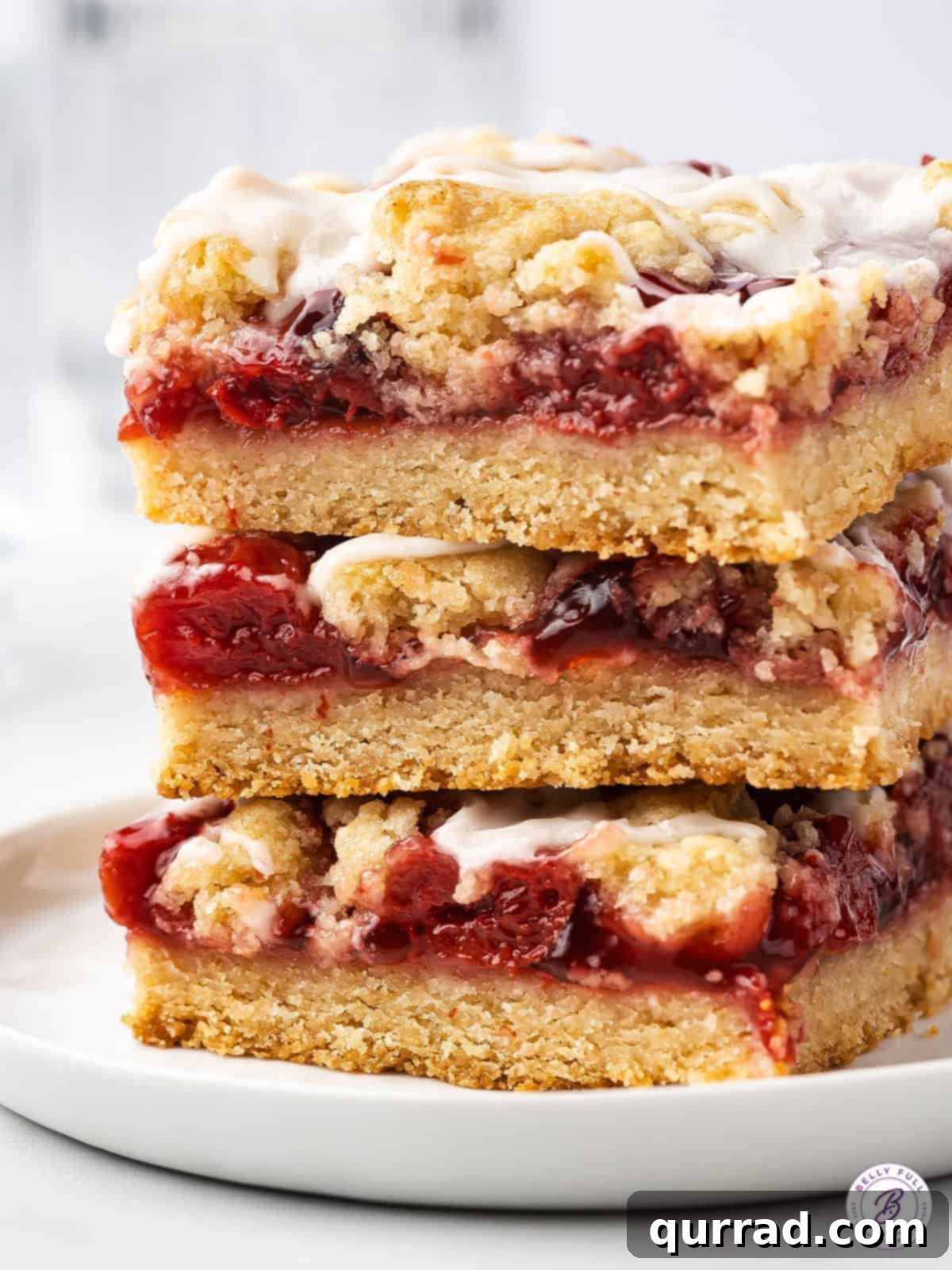 A tempting stack of Cherry Pie Bars, perfectly layered and drizzled with glaze. A beautiful stack of three cherry pie bars, showing off their perfect layers of crust, fruit filling, and crumb topping, with a delicate glaze.
