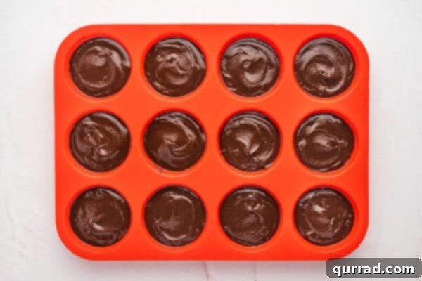 Melted chocolate mixture in a silicone muffin pan.