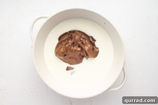 Heavy cream and Nutella being stirred into melted chocolate in a bowl.