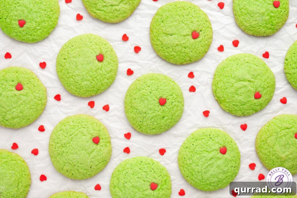 Overhead view of Grinch sugar cookies on a white background with red heart sprinkles