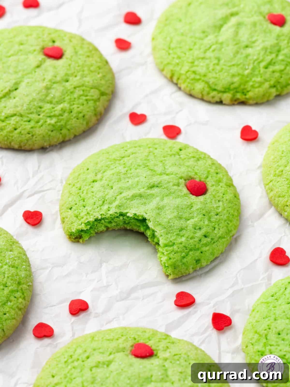 Grinch sugar cookies on a white background, one with a bite missing