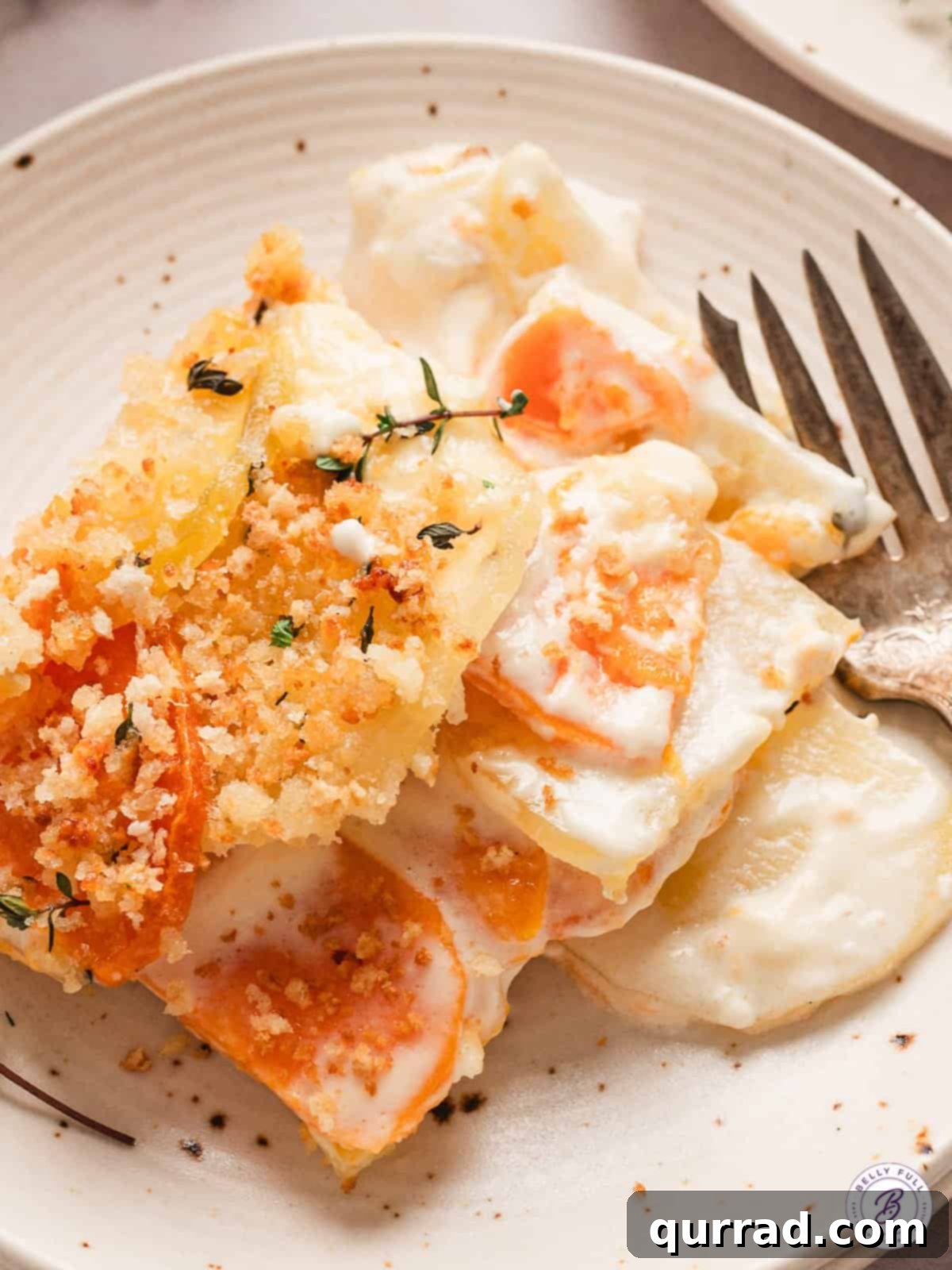 Yukon and Sweet Potato Gratin features layers of buttery Yukon gold potatoes and sweet garnet yams in a creamy sauce. Easy & impressive! A serving of Yukon and sweet potato gratin on a plate, showcasing its golden brown topping and layered interior.