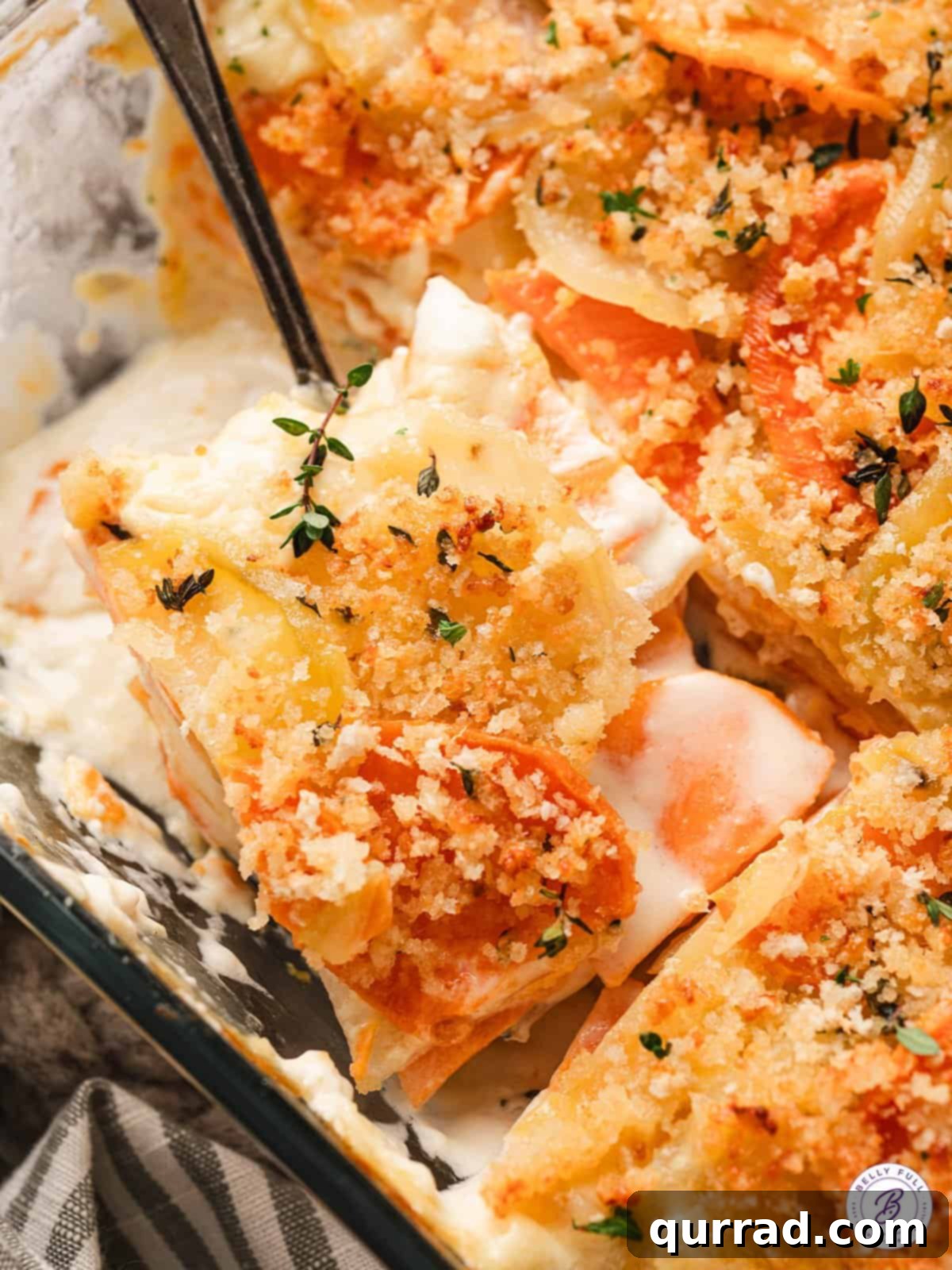 Yukon and Sweet Potato Gratin features layers of buttery Yukon gold potatoes and sweet garnet yams in a creamy sauce. Easy & impressive! A slice of Yukon gold and sweet potato gratin being served from the baking dish, showing its layered texture.