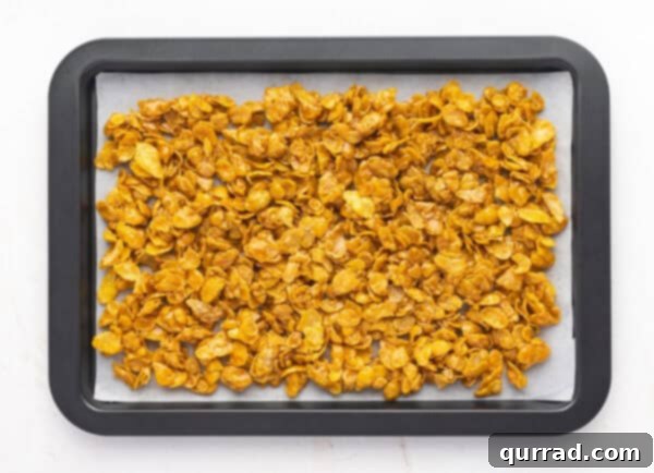Crispy Cornflake Chocolate Bark 11 Caramel-coated cornflakes spread evenly on a parchment-lined baking sheet