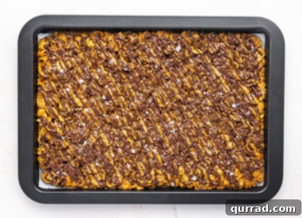 Crispy Cornflake Chocolate Bark 14 Overhead view of cornflake chocolate brittle on a baking sheet after chocolate has set, ready to be broken
