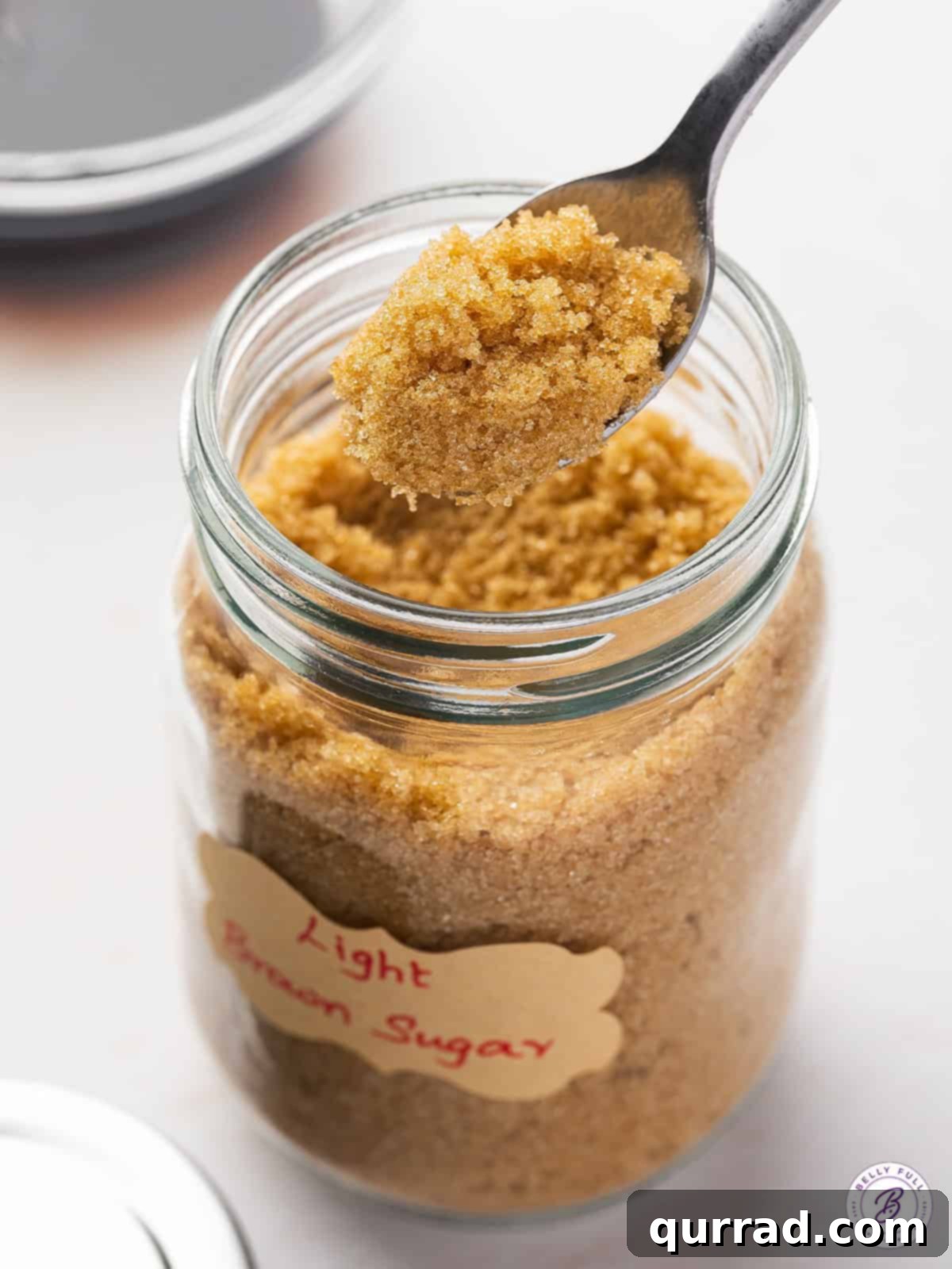 A spoon of homemade brown sugar above a jar of brown sugar
