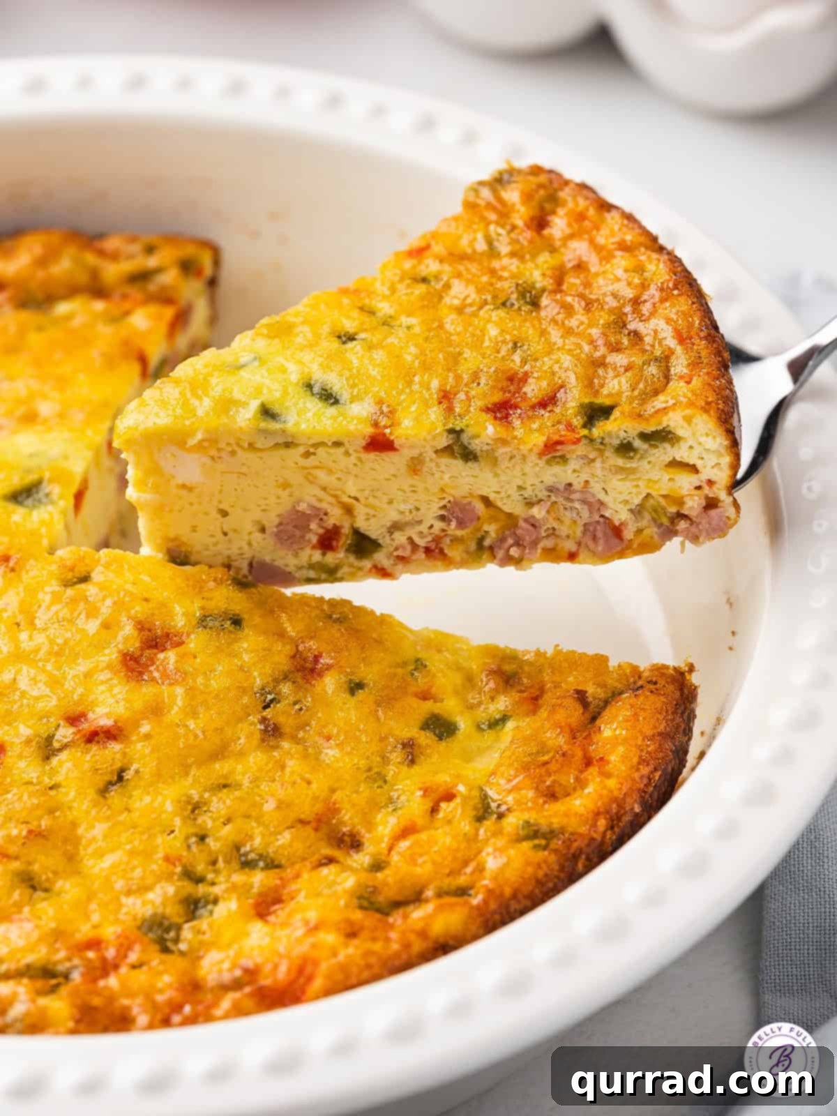 Made with diced peppers, onions, and ham, this Baked Denver Omelet is quick, easy, and great for serving a crowd. Serving a slice of baked Denver omelet, showcasing the layers of ham, peppers, onions, and cheese within the fluffy egg base.