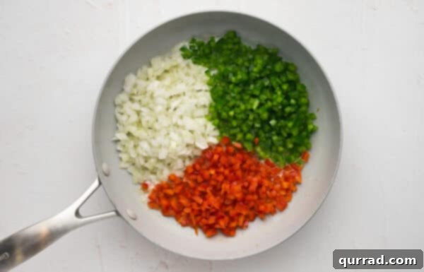 Diced red and green peppers and onions in a skillet, gently sautéing