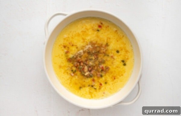 Spices, eggs, and vegetable mixture poured into a baking dish
