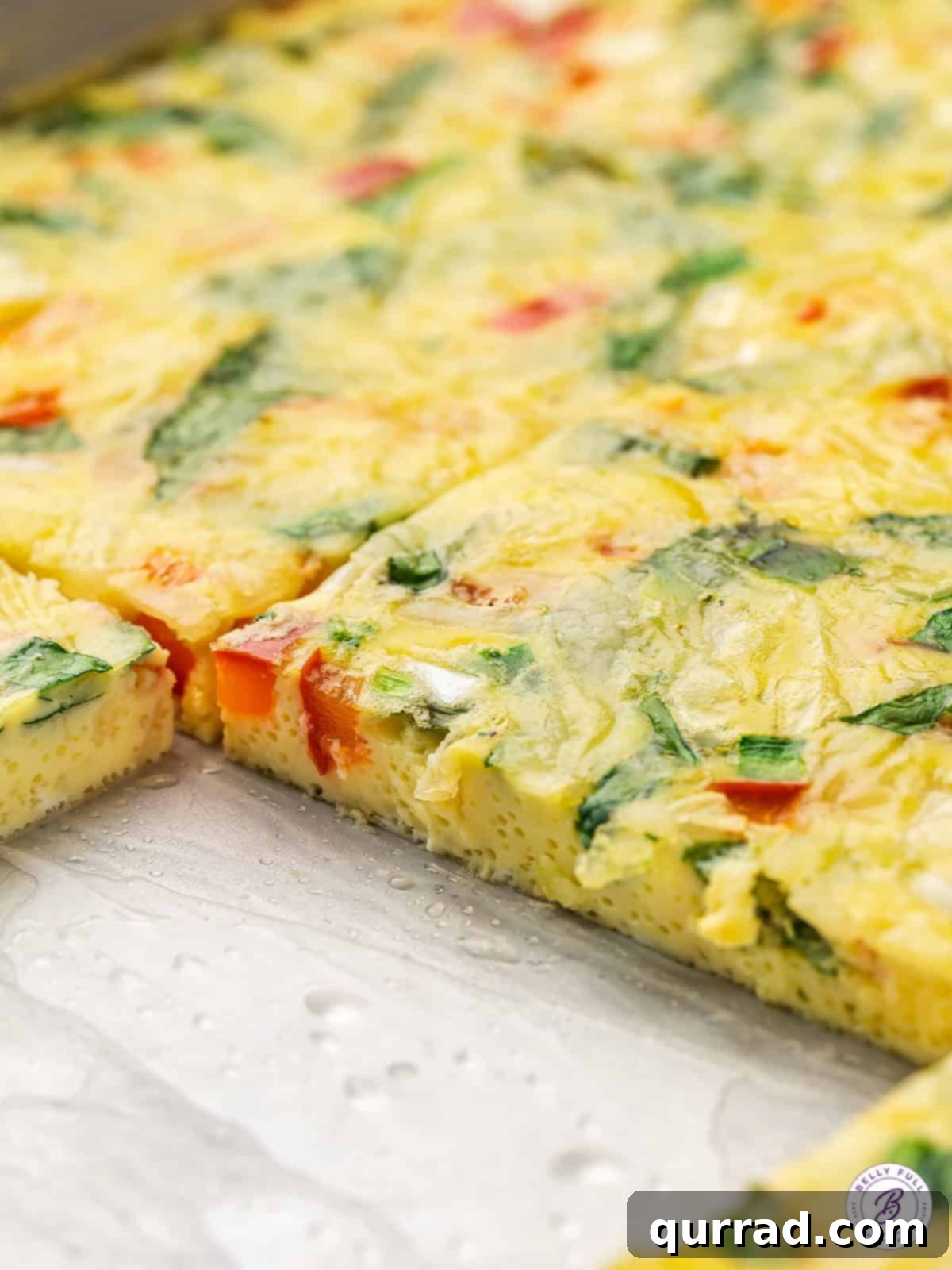Eggs, cheese, and veggies make this Sheet Pan Egg Frittata an easy, filling breakfast that's perfect for serving a crowd. A sheet pan frittata with a slice missing
