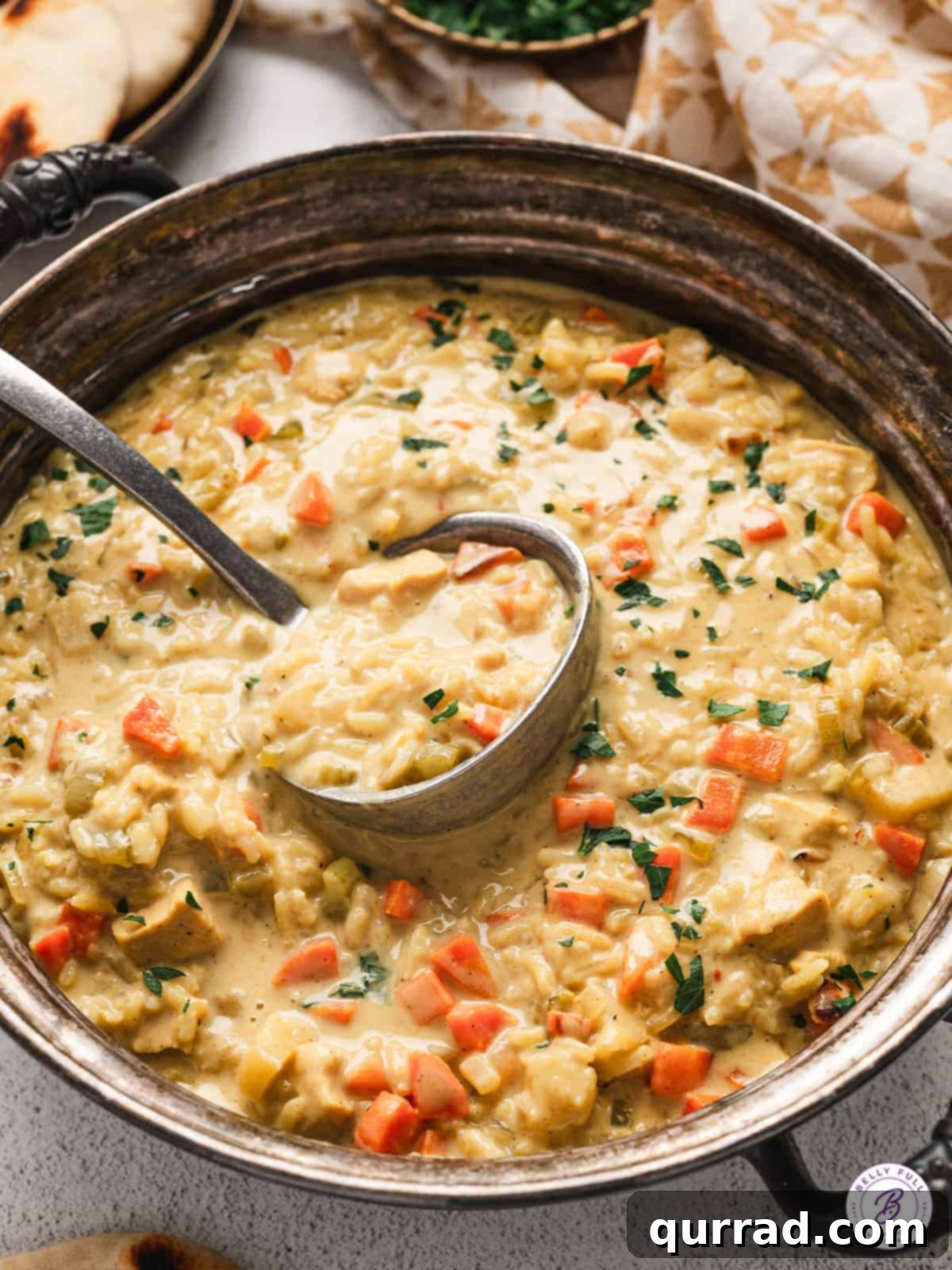 Experience the warmth of homemade Mulligatawny Soup, crafted with chicken, rice, and authentic curry powder for a truly easy and hearty Indian delight! Overhead view of a pot of Mulligatawny Soup with a ladle, showcasing its rich, creamy texture and vibrant color.