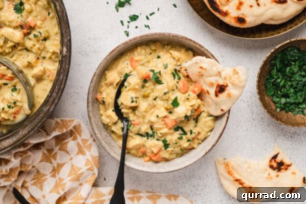 A perfectly portioned bowl of Mulligatawny Soup, garnished and ready to be served alongside a piece of fluffy naan bread.