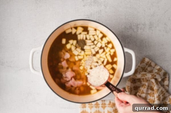 Adding small cubed chicken to a pot filled with simmering broth and vegetables, enhancing the heartiness of the soup.